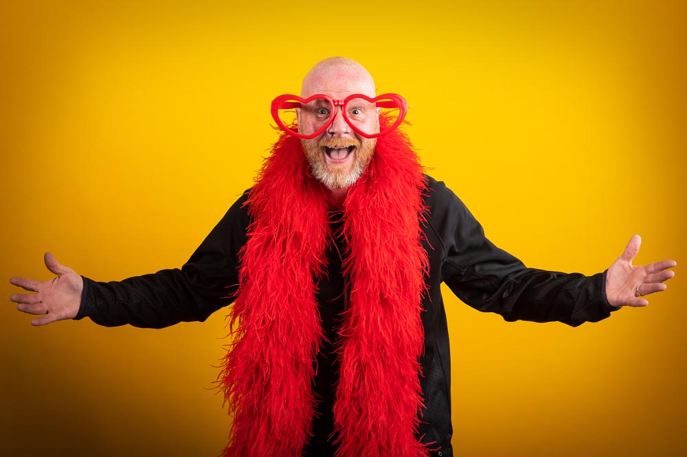 Photographer Mat Hayward wearing oversized red glasses and a red feather boa